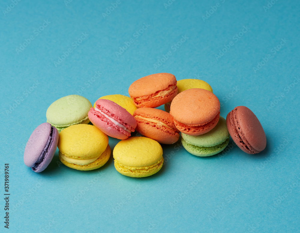 stack of multi-colored round baked macarons cakes on a blue background stack of multi-colored round baked macarons cakes on a blue background