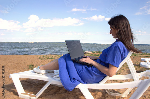 Young woman using laptop computer on a beach. Freelance work concept © Yekatseryna