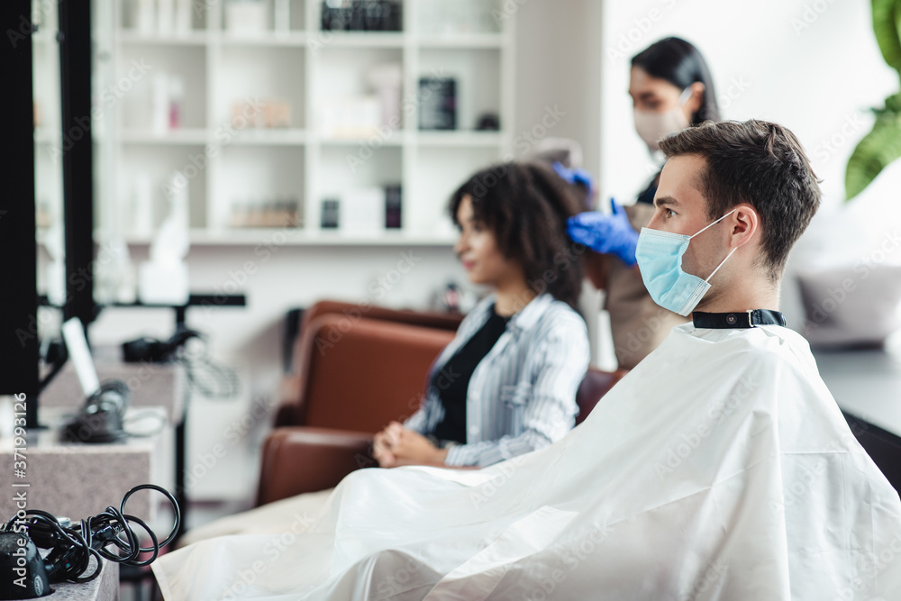 Man in medical mask sitting at hairdressers, waiting for master Man in medical mask sitting at hairdressers, waiting for master