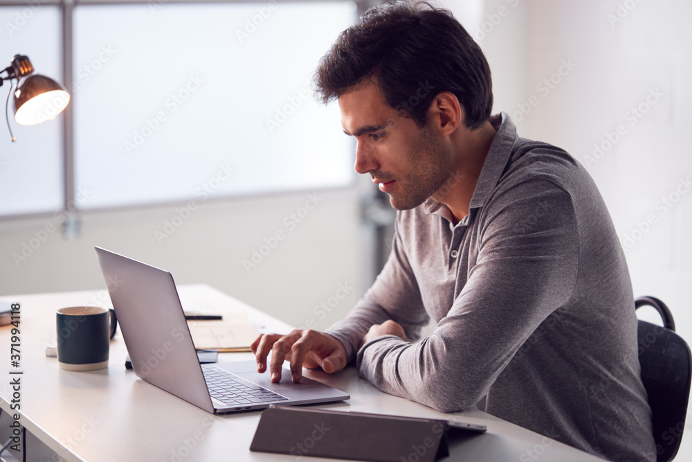 Businessman Working On Laptop At Desk In Modern Office Businessman Working On Laptop At Desk In Modern Office