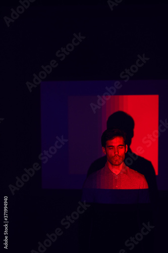 Studio Shot Of Man With Eyes Closed Illuminated By Red Light
