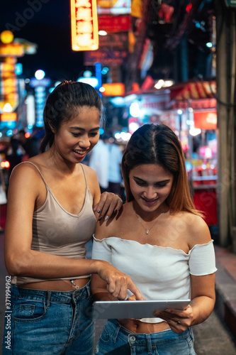 Girls in Bangkok at night looking at digital tablet stock photo © Tijana
