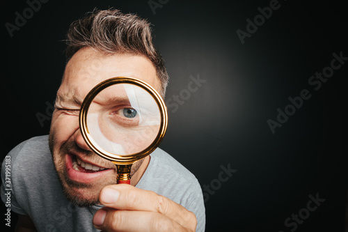man see through magnifying glass on the black backgrounds. Big man eye photo