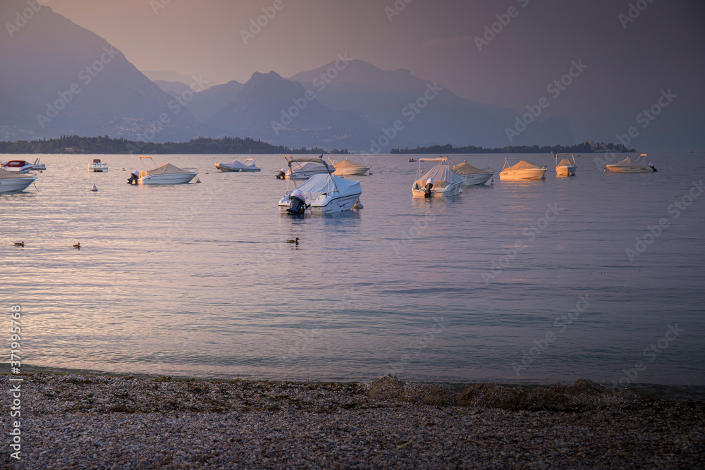 Lake view at pink sunset with  still boats from Manerba del Garda, Garda lake, Lombardia, Italy. Background with pastel tones.