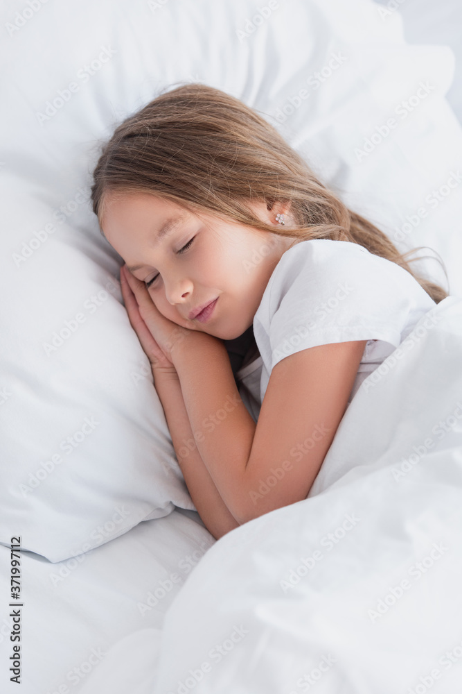 child sleeping on white bedding in morning
