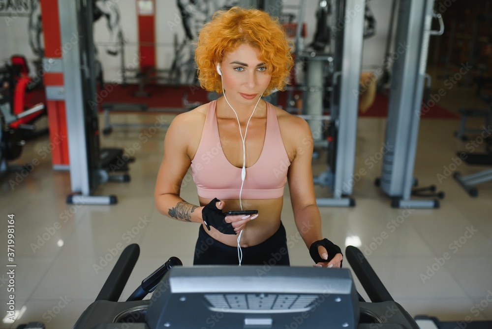 Fototapeta premium attractive young woman runs on a treadmill, is engaged in fitness sport club