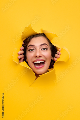 Excited woman looking through hole in paper © kegfire
