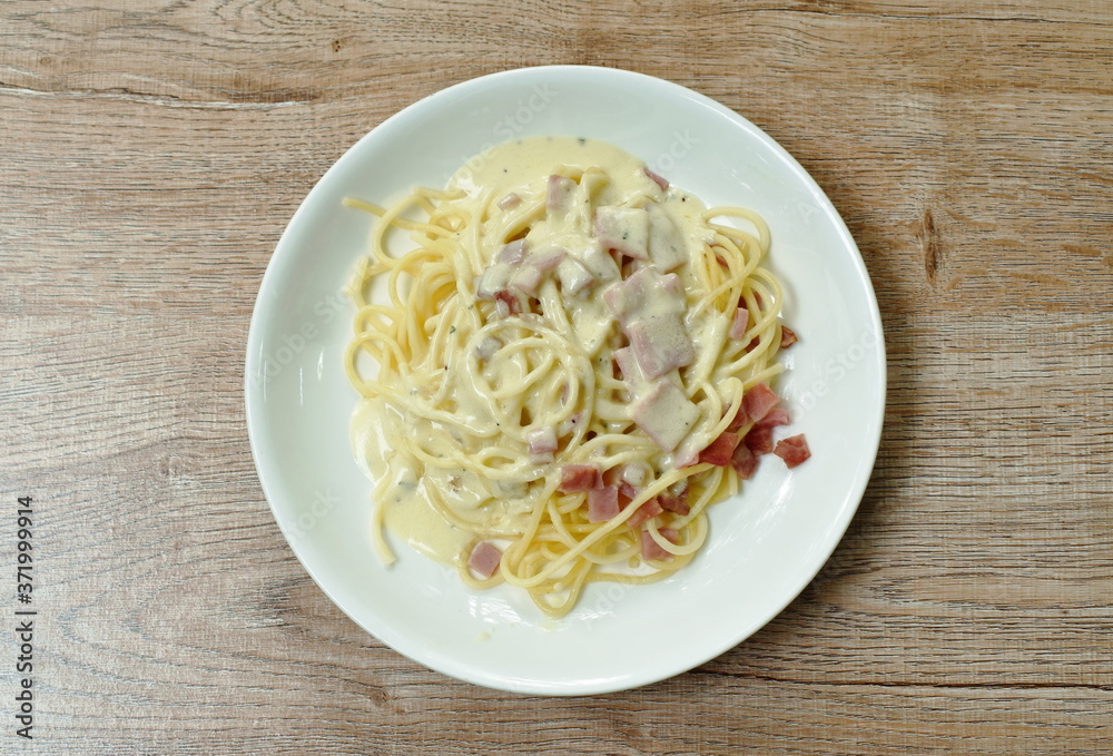 spaghetti white cream sauce topping slice ham pork on plate