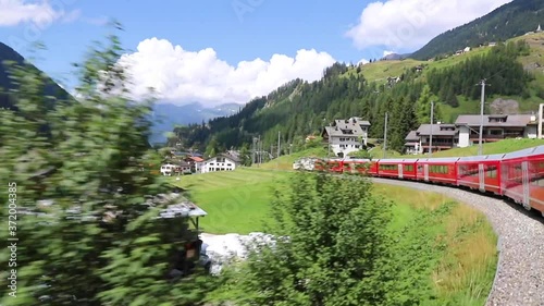 Picturesque villages and mountains in Swiss Alps areas, Switzerland, seen through the window of a red train