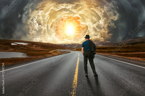 Mann auf einer einsamen Landstraße beobachtet die hereinbrechende Apokalypse photo