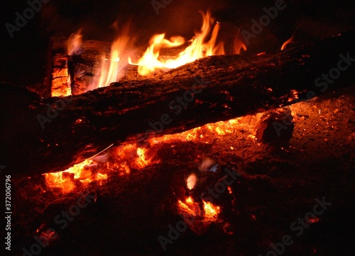 Old wooden beam used as firewood in a bonfire with embers.