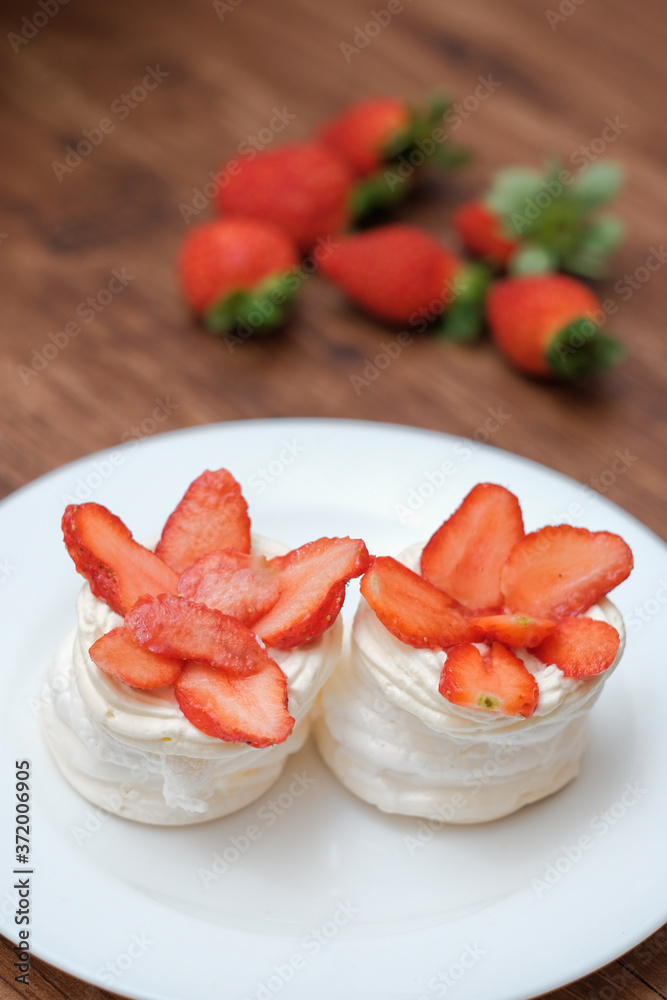 Mini pavlovas with whipped cream and fresh strawberry