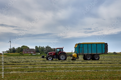Bauer auf seinem Traktor bei der Heuernte, an einem sonnigen Tag