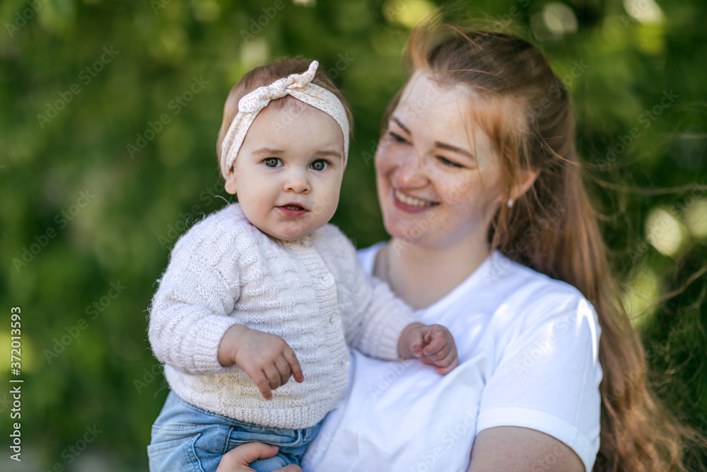 A young mother walks with a one-year-old baby, holds him in her arms, hugs. Communication with the child for his harmonious development