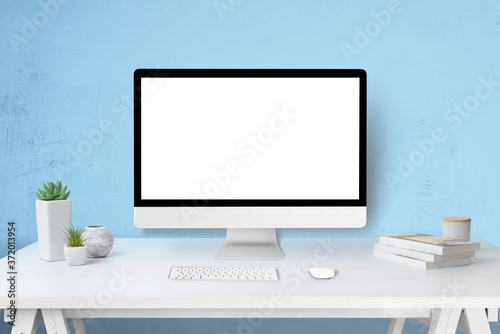 Modern computer display mockup on work desk. Isolated screen for web site design promotion concept. Blue wall in background