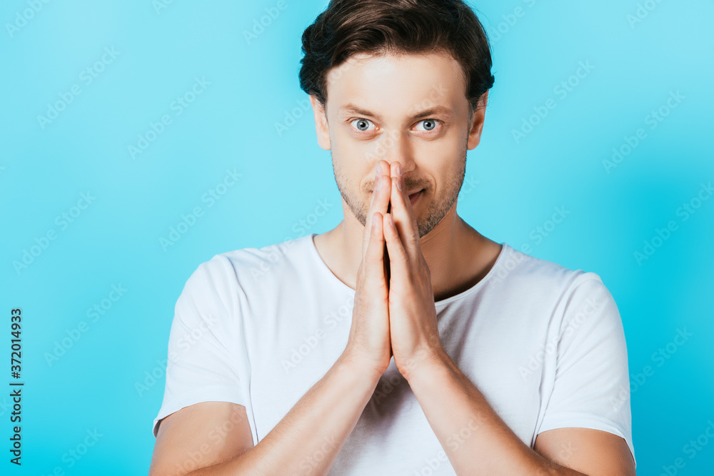 Man showing please gesture while looking at camera on blue background Man showing please gesture while looking at camera on blue background