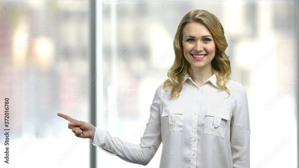 Pretty smiling woman pointing with finger to copy space. Advertising and promotion concept. Get your discount for holiday. Pretty smiling woman pointing with finger to copy space. Advertising and promotion concept. Get your discount for holiday.
