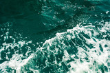 Dark turquoise sea water with white foam texture on the surface. Background image.