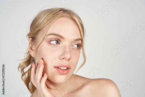 Blonde woman with bare shoulders clean skin lifestyle close-up cropped view light background