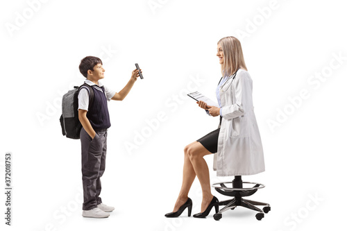 Full length profile shot of a schoolboy standing and showing a mobile phone to a female pediatrician doctor