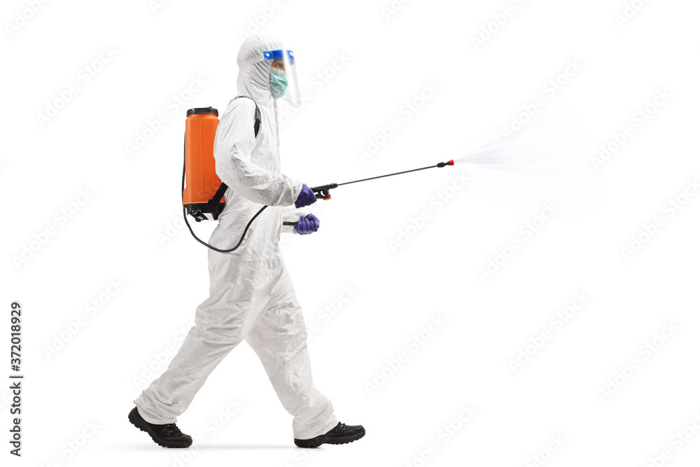 Specialist in a hazmat suit walking and spraying a disinfectant