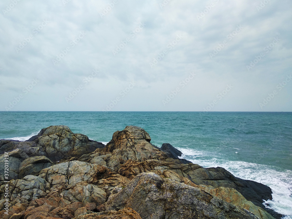 brown rocks on the blue sea shore in cloudy day