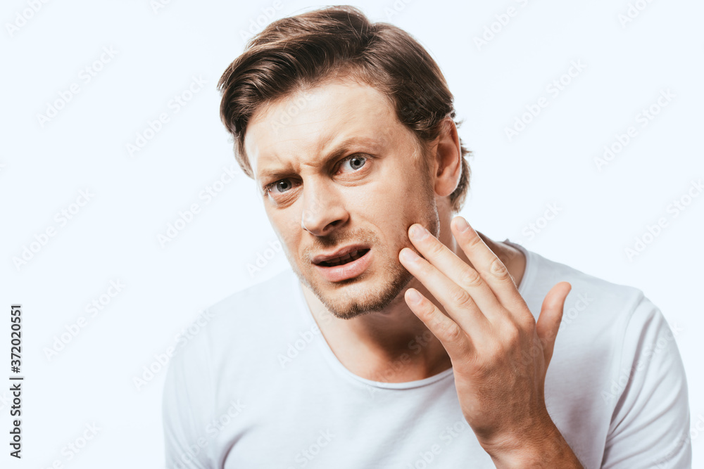 Worried man looking at camera and touching skin on cheek isolated on white Worried man looking at camera and touching skin on cheek isolated on white