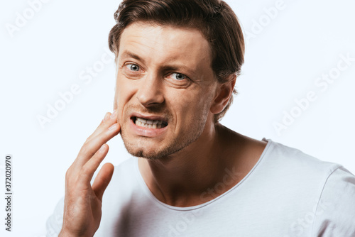 Dissatisfied man touching skin on cheek isolated on white