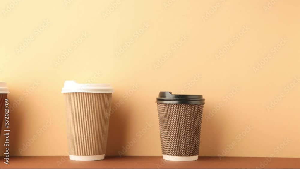 A lot of disposable cups for coffee and tea change places. Nice catering for a coffee shop. Video footage stop motion timelapse. Beige background.