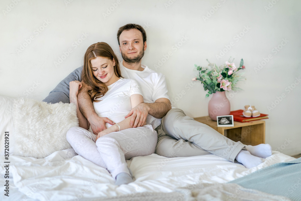 Family waiting for the baby. Husband and pregnant wife in a bright interior hug and smile. Pregnancy planning and preparation for childbirth Family waiting for the baby. Husband and pregnant wife in a bright interior hug and smile. Pregnancy planning and preparation for childbirth