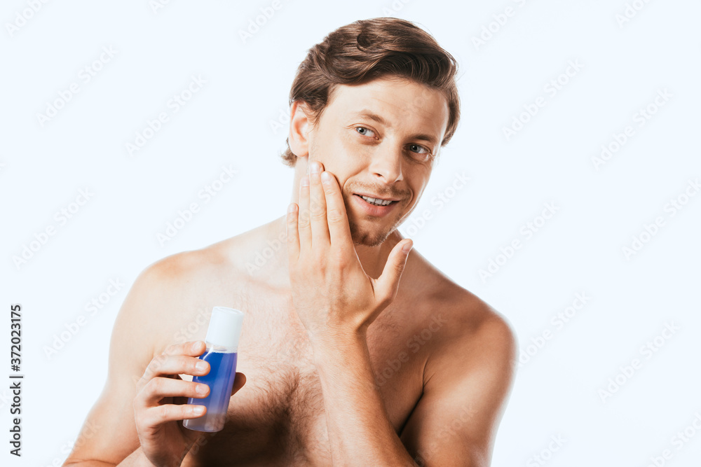 Shirtless man touching skin while holding bottle of toner isolated on white Shirtless man touching skin while holding bottle of toner isolated on white