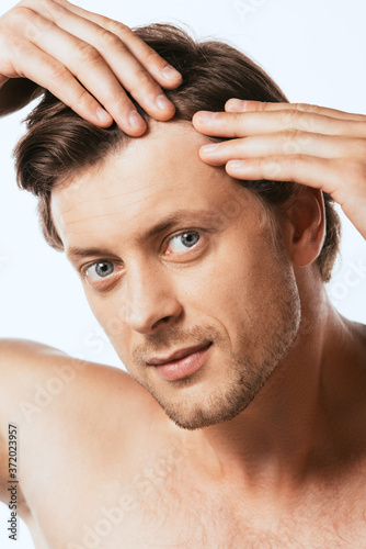 Shirtless man touching hair and looking at camera isolated on white