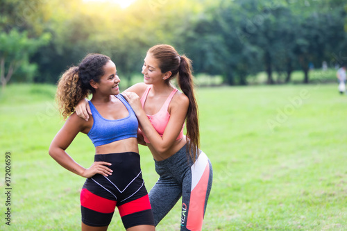 Fototapeta Naklejka Na Ścianę i Meble -  Two girlfriends workout in sunny park. Young woman african american and caucasian woman workout outdoor