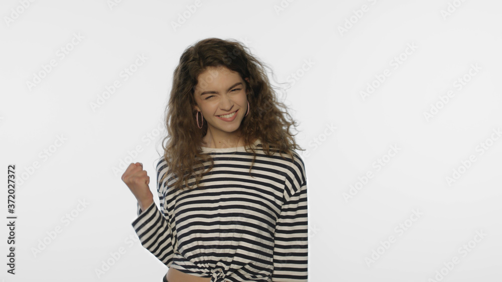 Young woman yes gesture in studio. Portrait of happy girl celebrating success Young woman yes gesture in studio. Portrait of happy girl celebrating success