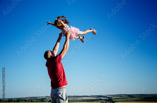 Strong paternal arms. Happy child with a small child are playing. Summer and children. A happy family. The child happily plays with his father. Dad and daughter close up.