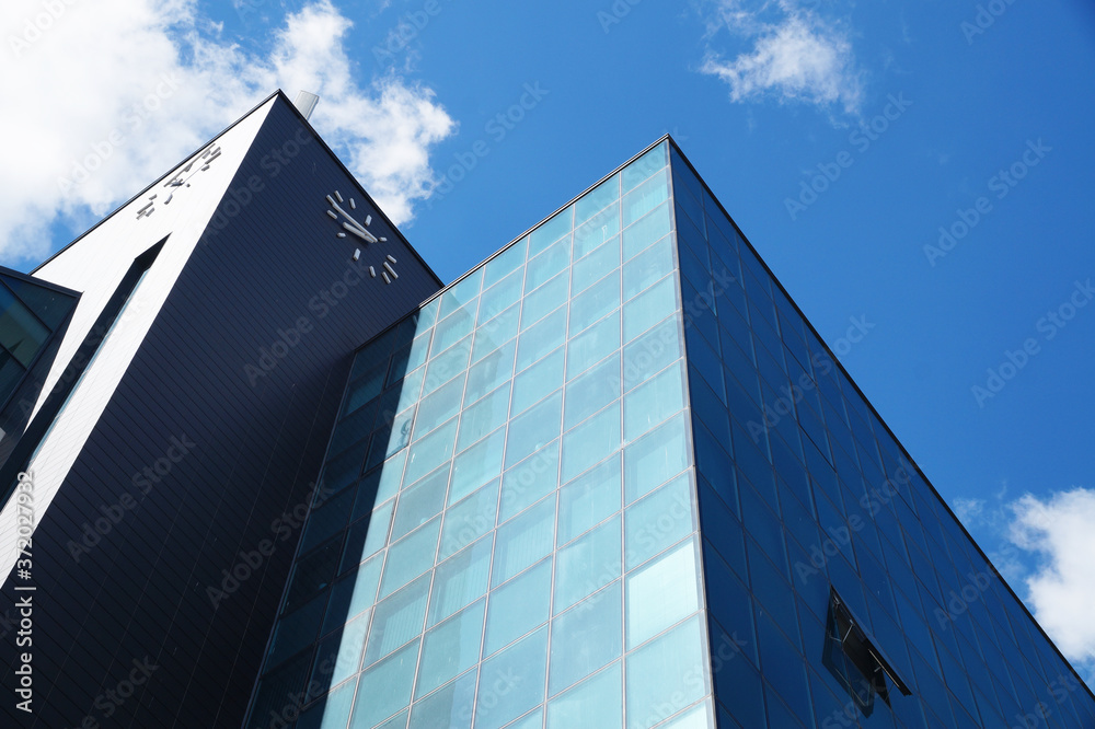 modern glass facade of a skyscraper against the backdrop of a sunny cloudy sky.
