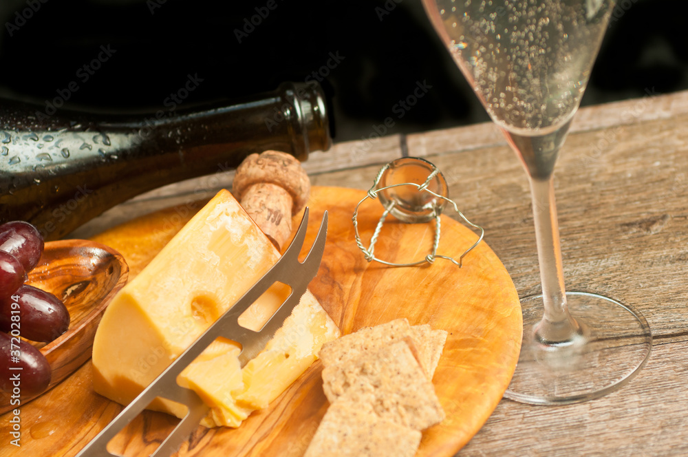 top view, close distance of a glass of champaign and a rare wood plater of wedge of Swiss cheese