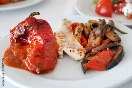 fish fillet with baked peppers and vegetables on a plate