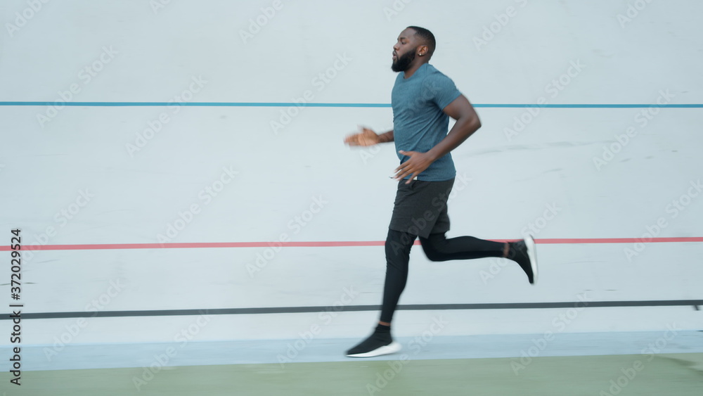 African american man jogging on stadium. Runner doing cardio workout outdoors African american man jogging on stadium. Runner doing cardio workout outdoors