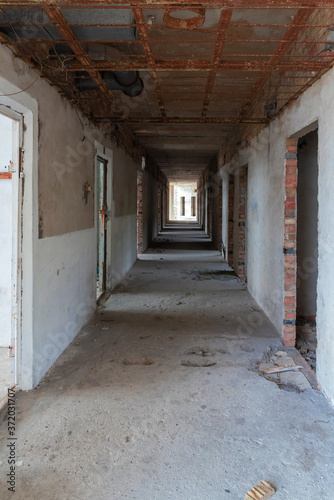 Corridor of a destroyed old hotel with broken doors and damaged floor