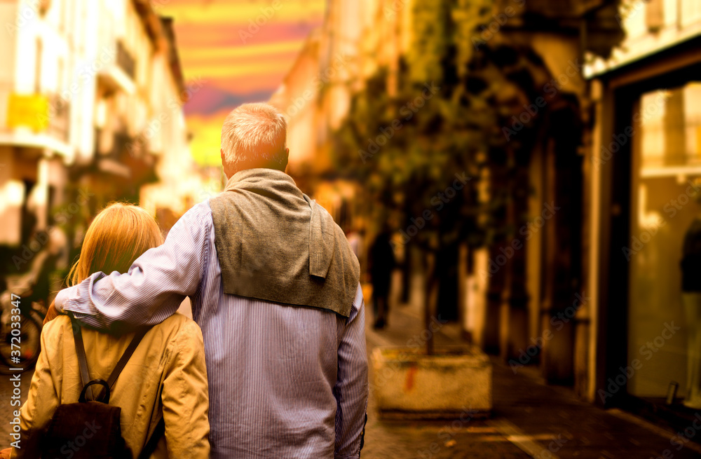 Old dreamy couple carefree walking along the streets of the old city at sunset Old dreamy couple carefree walking along the streets of the old city at sunset