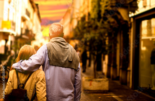 Old dreamy couple carefree walking along the streets of the old city at sunset