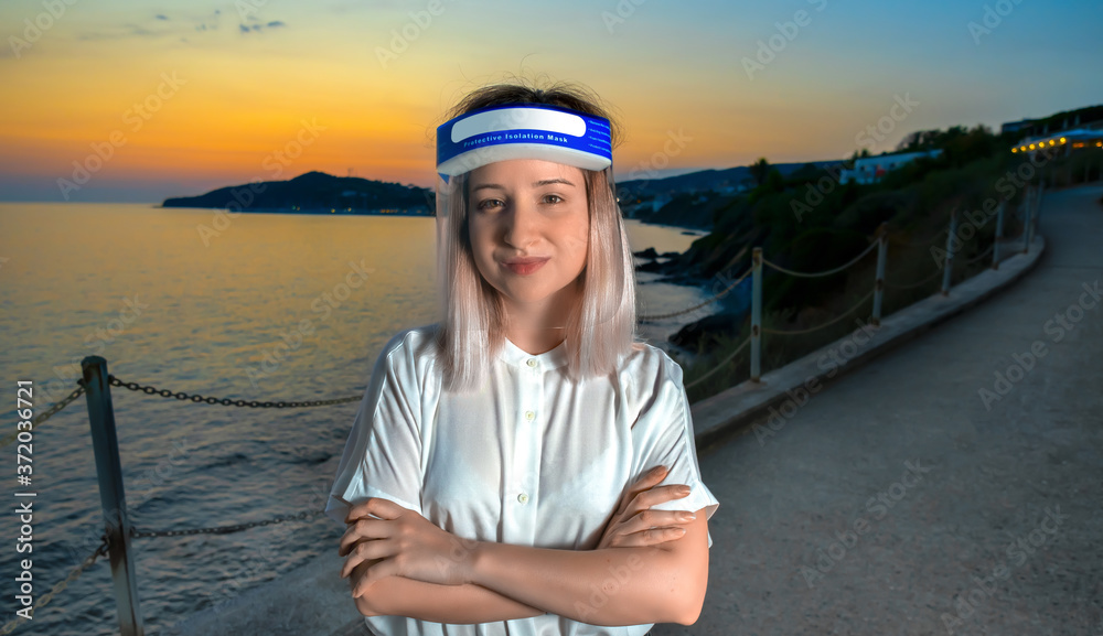 Female in white blouse, transparent face shield, isolation mask on sea sunset background. Health protection and social distance concept. Summer time after quarantine