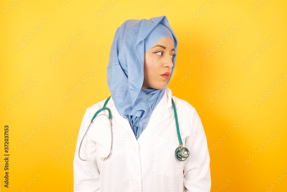 Φωτογραφία Close up side profile photo Young arab doctor woman wearing medical uniform standing over yellow background  ready to have a walk
