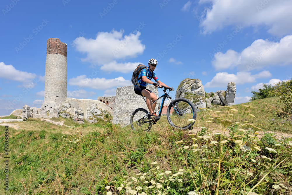 A man on a mountain bike on the hill of Olsztyn Castle. Poland.	