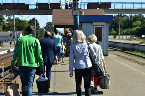 People walk in one direction on a railway platform. photo
