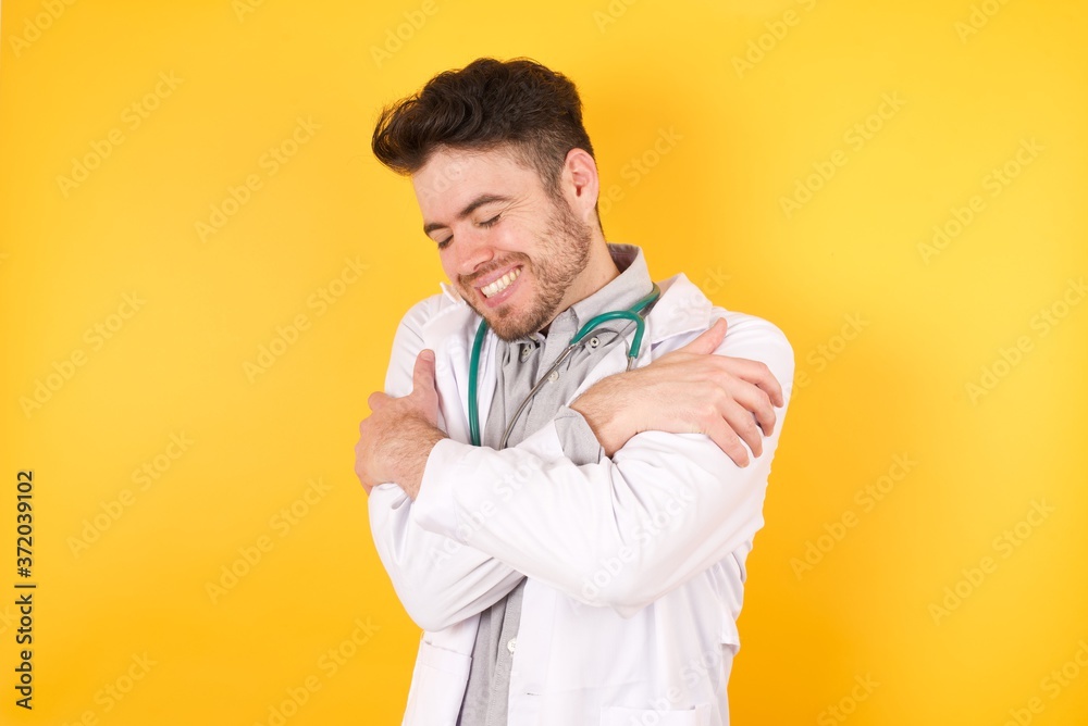 Young Caucasian doctor man wearing medical uniform, over isolated background Hugging oneself happy and positive, smiling confident. Self love and self care Young Caucasian doctor man wearing medical uniform, over isolated background Hugging oneself happy and positive, smiling confident. Self love and self care