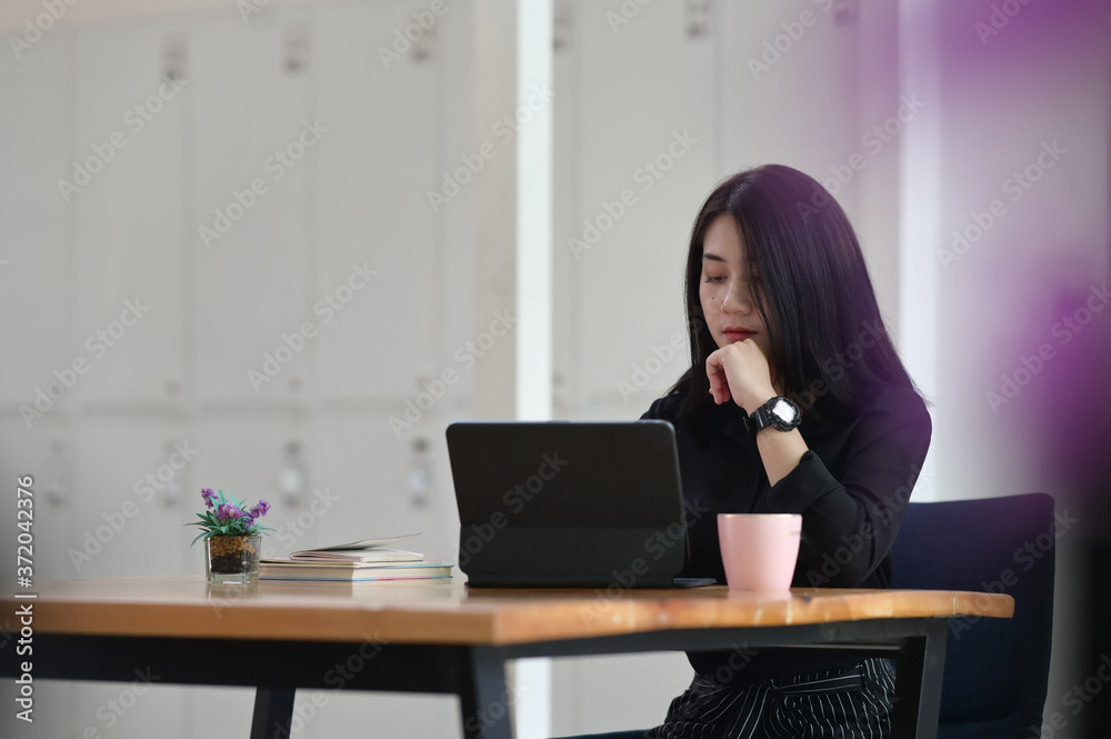 A businesswoman is using a computer tablet while sitting at the wooden working table. A businesswoman is using a computer tablet while sitting at the wooden working table.