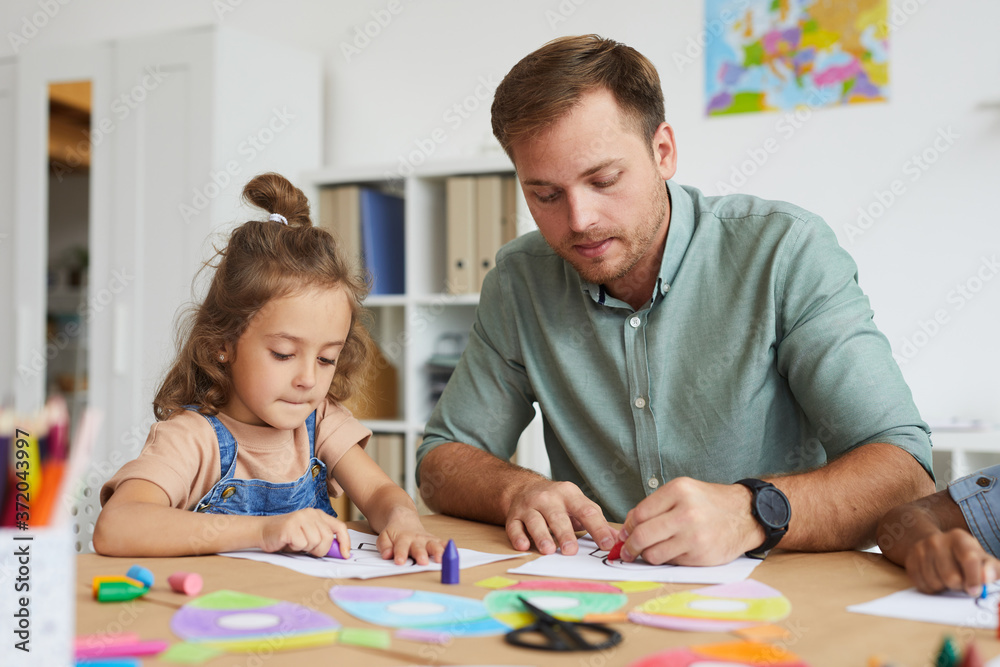 Portrait of young father drawing with little daughter while enjoying kindergarten class together Portrait of young father drawing with little daughter while enjoying kindergarten class together