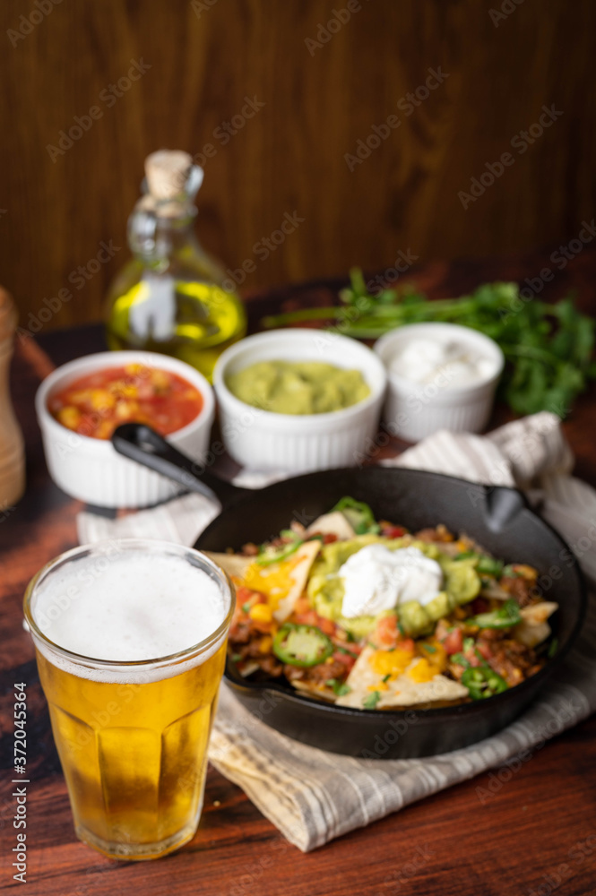 nacho in skillet pan with a glass of beer nacho in skillet pan with a glass of beer